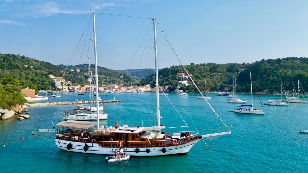 Gulet anchored in crystal-clear Greek waters with guests swimming